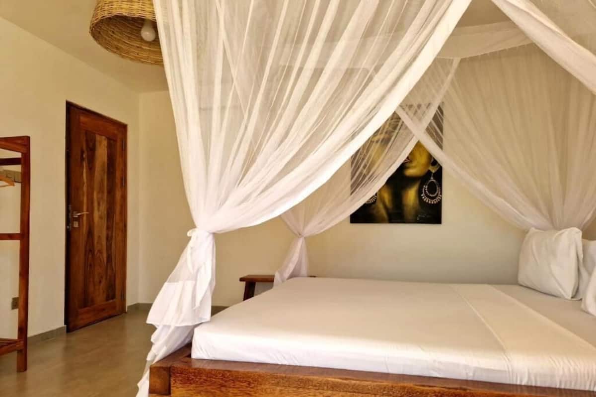 Un dormitorio con estructura de cama de madera, ropa de cama blanca y dosel.