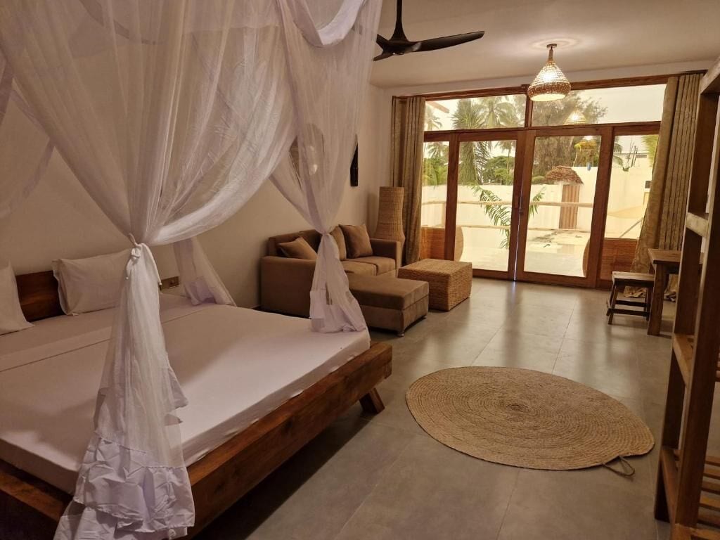 Un dormitorio con cama, ventilador de techo, ventana grande y vistas al exterior.