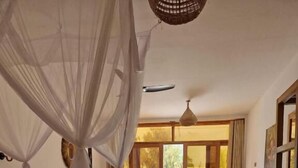 Un dormitorio con cama, dosel, alfombra redonda y vistas al exterior a través de un ventanal.