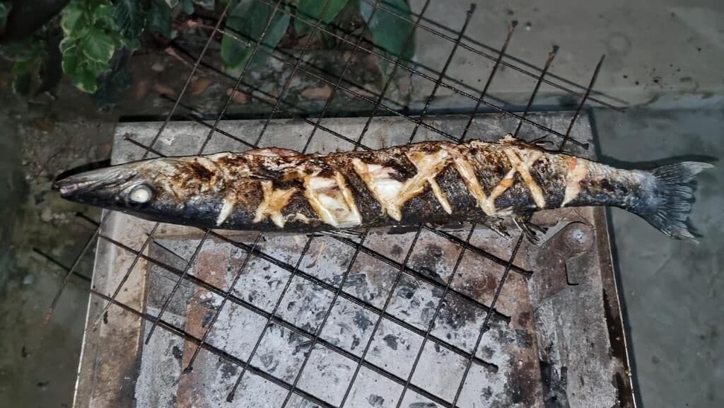 Un pescado a la parrilla sobre una rejilla de metal.