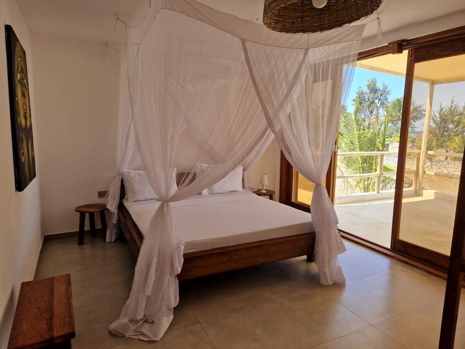A bedroom with a canopy bed, a small stool, and a bench.