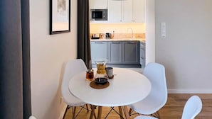 Een moderne keuken met witte kastjes, een magnetron en een koffiezetapparaat.