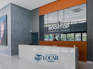 Taulell de recepció amb cartell per 'ROOFTOP AGAMENON PRINCE' i el logotip de 'LOCAR house'.