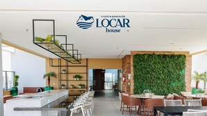 Un moderno vestíbulo de hotel con mostrador de recepción, zona de estar y una pared verde.