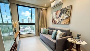 Una sala de estar moderna con un sofá, una mesita y un ventanal con vistas a la ciudad.