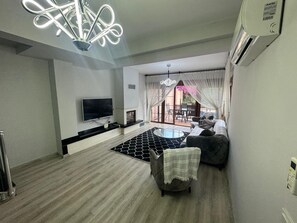 Ein modernes Wohnzimmer mit Flachbildfernseher, Kamin, rundem Couchtisch und einer Couch.