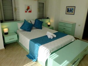 A bedroom with a bed, bedside tables, a bench, and wall art.