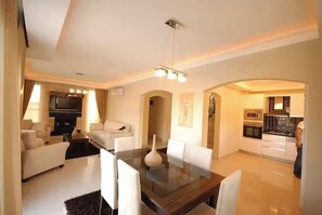 A modern living room with a dining area, kitchen, and a TV.