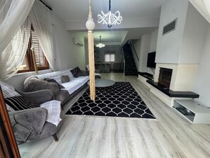 A modern living room with a sofa, a patterned rug, a chandelier, and a fireplace.