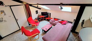 A compact living space with a sofa, red chairs, a TV, and a small table. - The Chalet des Côtes in the heart of nature. (Cornimont)