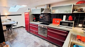 Eine moderne Küche mit Essbereich, einem roten Kühlschrank und einer Mikrowelle.