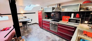 A modern kitchen with a dining area, a red refrigerator, and a microwave. - The Chalet des Côtes in the heart of nature. (Cornimont)