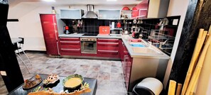 A modern kitchen with red cabinetry, a gas stove, a microwave, and a sink. - The Chalet des Côtes in the heart of nature. (Cornimont)