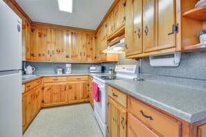 A kitchen with wooden cabinets, a refrigerator, a stove, a microwave, and a coffee maker. - Peaceful Home Near The Blue Ridge Mountains (Stuart)