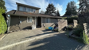 A two-story house with a brick driveway, a garage, and a wooden fence.