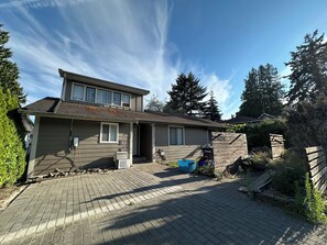 Ein zweistöckiges Haus mit Ziegelfahrweg, Garage und Holzzaun.