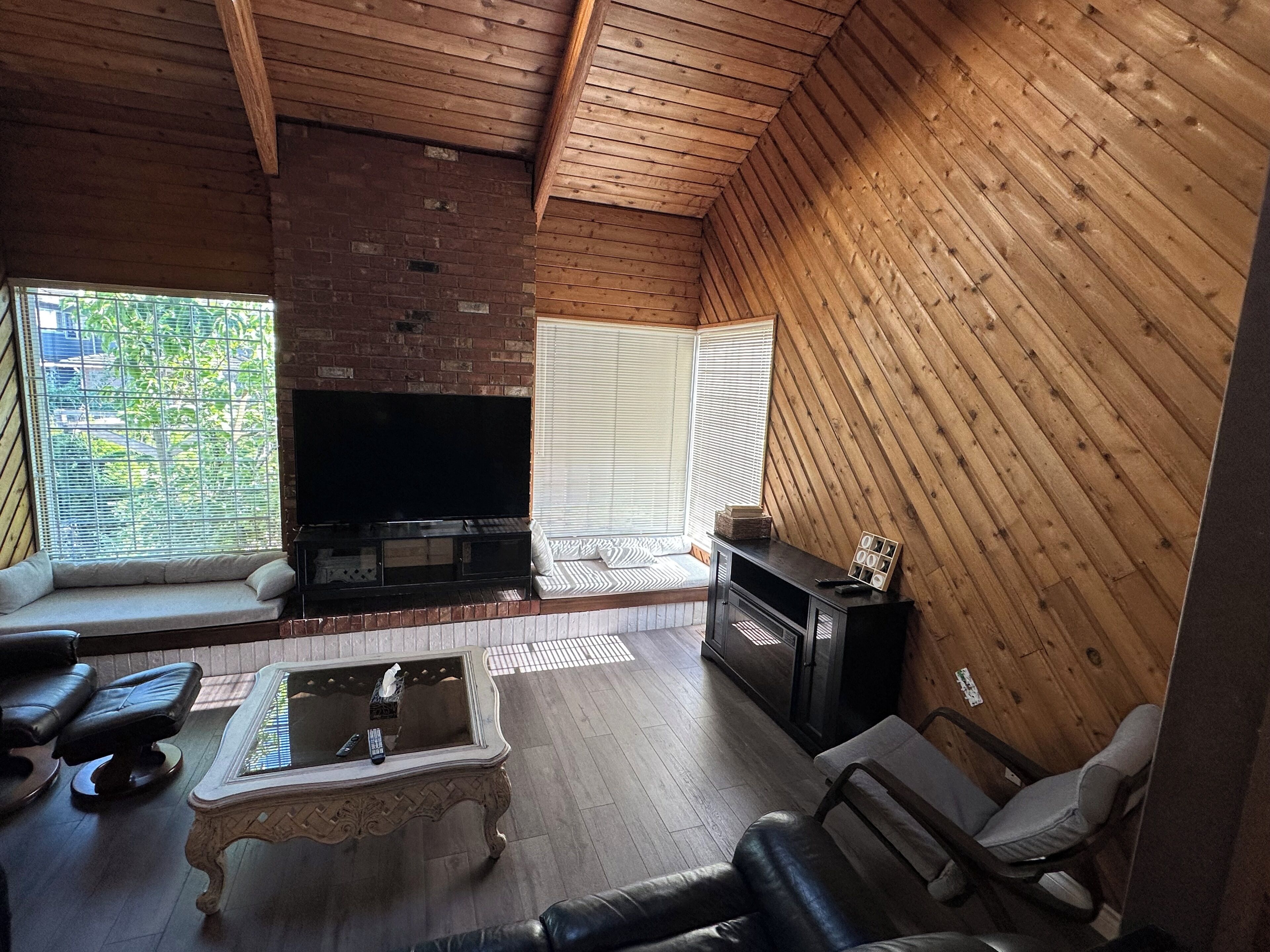 A cozy living room with a brick fireplace, a television, a sofa, and a coffee table.