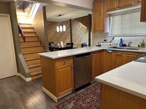 A modern kitchen with wooden cabinets, a dishwasher, and a dining area with a table and chairs. - few minutes walk to skytrain or transit.
6 minutes  to Metro town mall in a car (Burnaby)