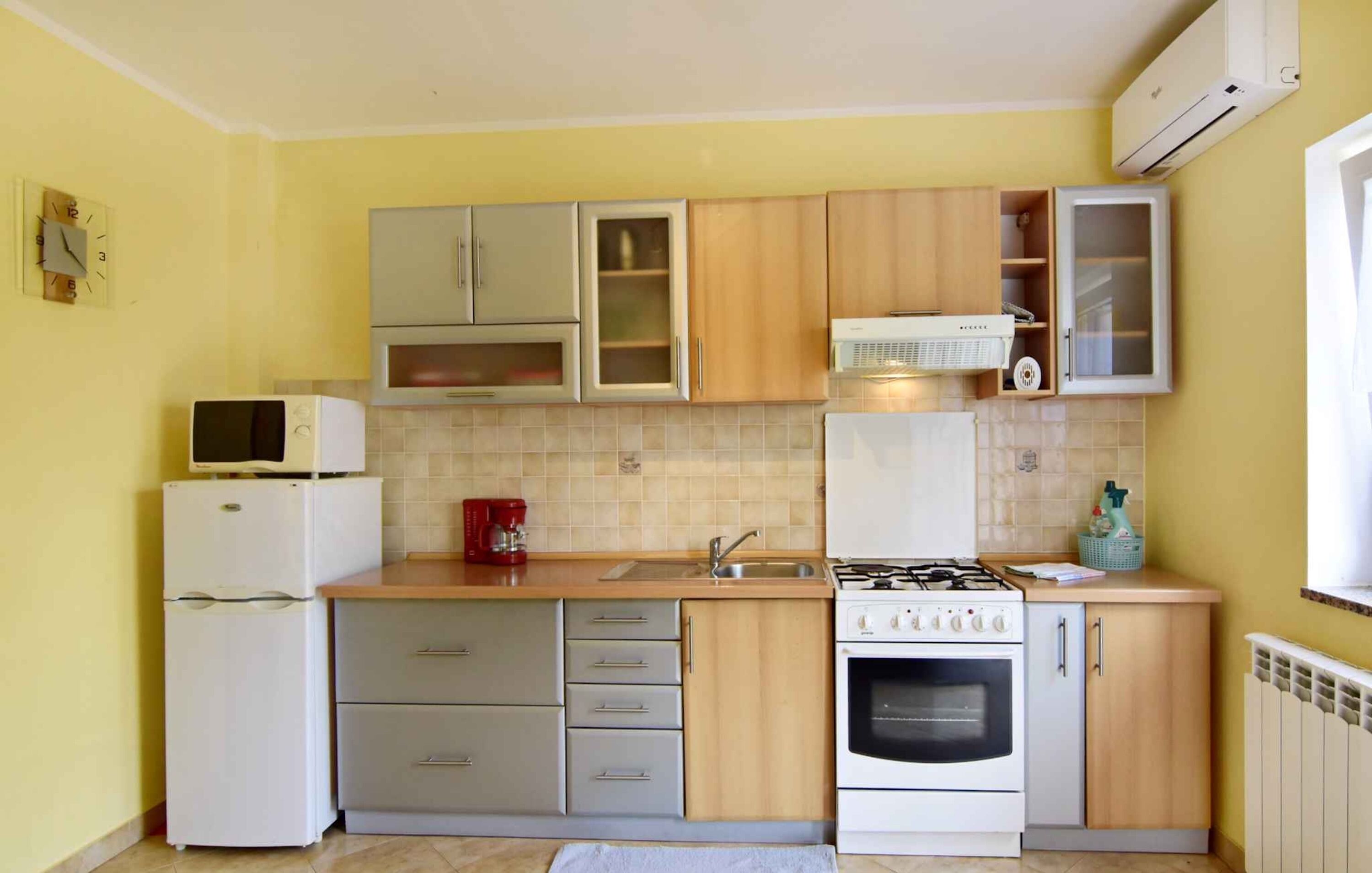 A compact kitchen with a refrigerator, stove, sink, and cabinets.