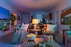 Ein gemütliches Wohnzimmer mit einer großen Schüssel Popcorn, einem Tisch mit Getränken und einem Bild an der Wand.