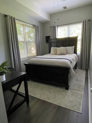 Une chambre à coucher avec un lit, un bureau et une fenêtre avec des rideaux.