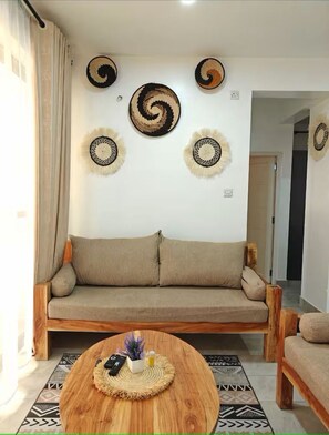 Una sala de estar con un sofá, una mesa de centro con un objeto decorativo y una obra de arte en la pared.
