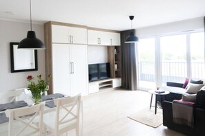 Ein modernes Wohnzimmer mit Essbereich, einem Flachbildfernseher und einem Balkon mit Blick.