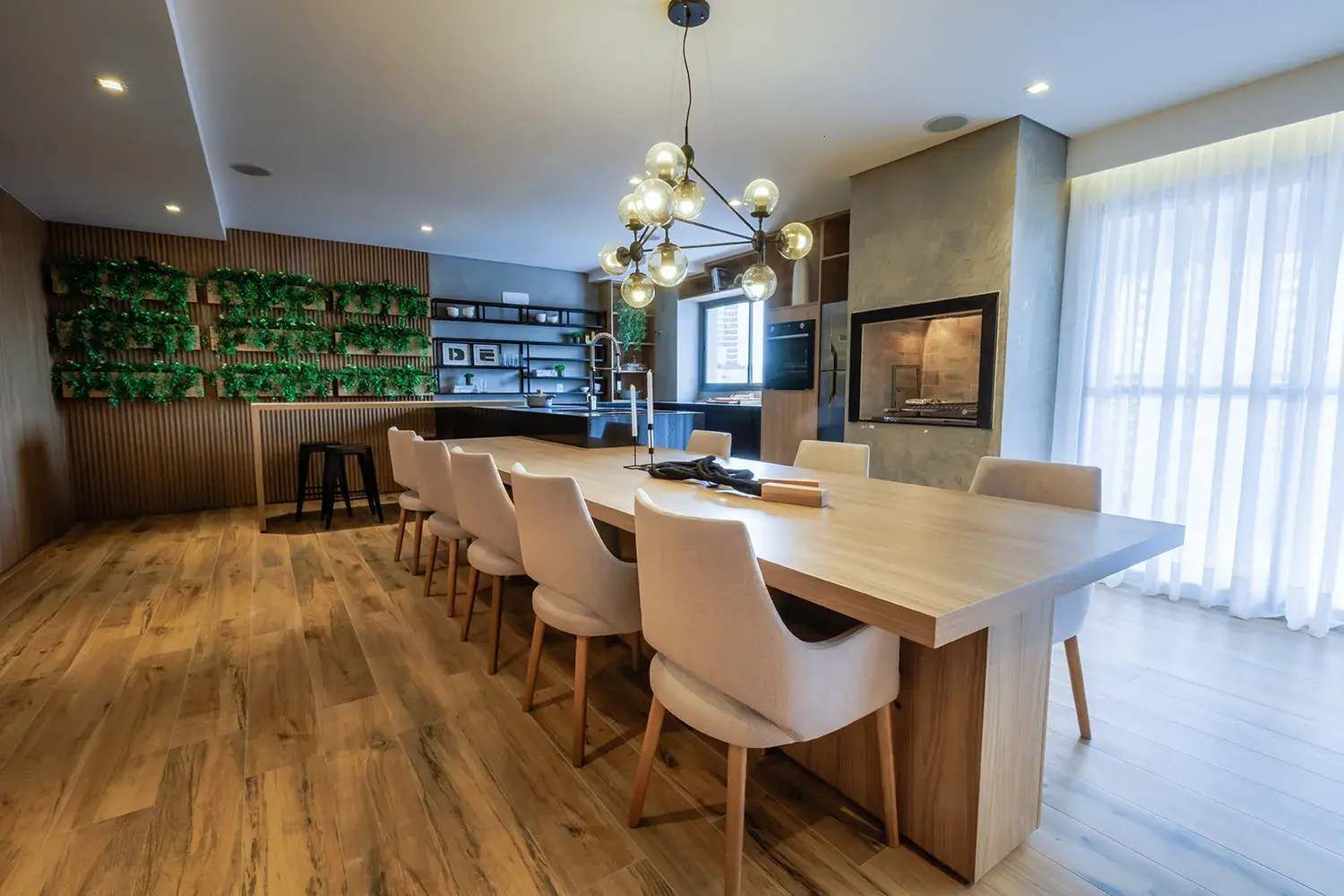 A modern kitchen with a central island, wooden flooring, and a green wall decoration.