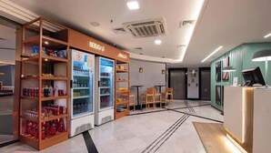 Eine Hotelhalle mit Rezeption, Sitzgelegenheiten und Getränkeautomaten.