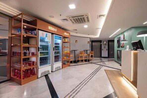 Un hall de hotel con mostrador de recepción, zona de estar y máquinas expendedoras.