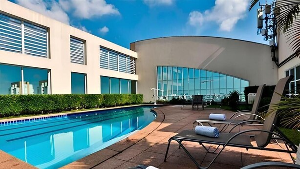 Ein Schwimmbad mit Liegestühlen und ein modernes Gebäude mit großen Fenstern.