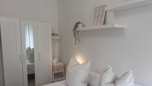 A bedroom with a bed, white wardrobe, bedside table, and a shelf with decorative items. - Terracina Central Rooms (Terracina)