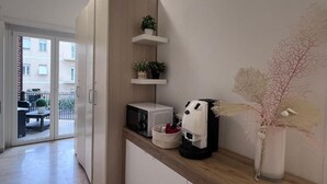 A kitchenette with a microwave, coffee maker, and potted plants on a wooden countertop. - Terracina Central Rooms (Terracina)