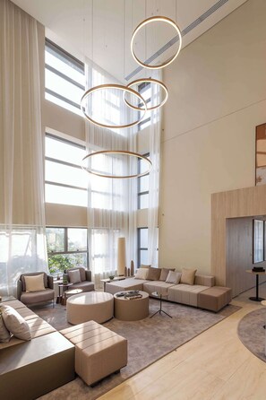 A spacious living area with a large sectional sofa, round coffee tables, and a modern chandelier. - Studio Completo a 1km do Ibirapuera | ZH1309 (Jardim Paulista)