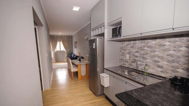 A modern kitchen with a refrigerator, microwave, and sink. There is a dining area with a table and chairs.