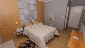 A bedroom with a bed, bedside tables, a mirror, a wooden floor, and a door.
