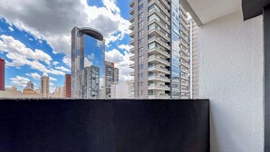 A high-rise building with a curved glass facade, a balcony with a black railing, and a white textured wall. - #MY606 | Cyclinn Pinheiros (Pinheiros)