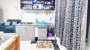 A compact living space with a kitchenette, a sofa, and a patterned curtain. - Modern Airport Studio Near SGR & Moi Airport (Mombasa)