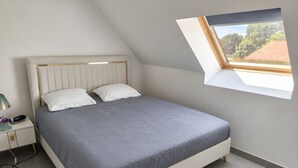 A bedroom with a bed, a nightstand, a lamp, and a skylight. - Family home near Chambord (Mont-près-Chambord)