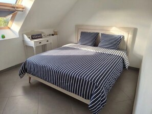 Een slaapkamer met een bed, een bureau en een raam.