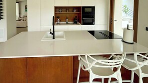 Una cocina moderna con una isla central, horno empotrado y un mueble de madera.