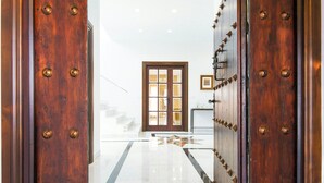 Un pasillo con una puerta de madera, una puerta de cristal y una escalera que conduce a otra habitación.
