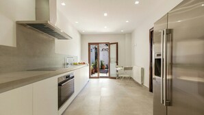 Una cocina moderna con horno empotrado, refrigerador de acero inoxidable y un comedor con mesa y sillas.