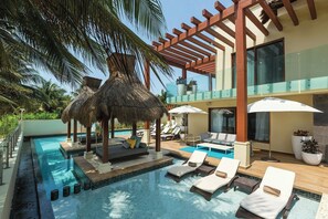 A pool area with lounge chairs, a thatched-roof structure, and a glass balustrade. - Villa Esmeralda - Luxury Beachfront Escape (Puerto Morelos)