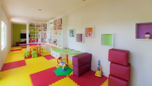 Un cuarto de juegos infantil con piso colorido, una mesa de juegos y varios juguetes.