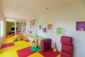 A children's playroom with a colorful floor, a play table, and various toys. - Villa Esmeralda - Luxury Beachfront Escape (Puerto Morelos)