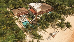 Vista aérea de un resort con piscina, sillas de descanso y palmeras.