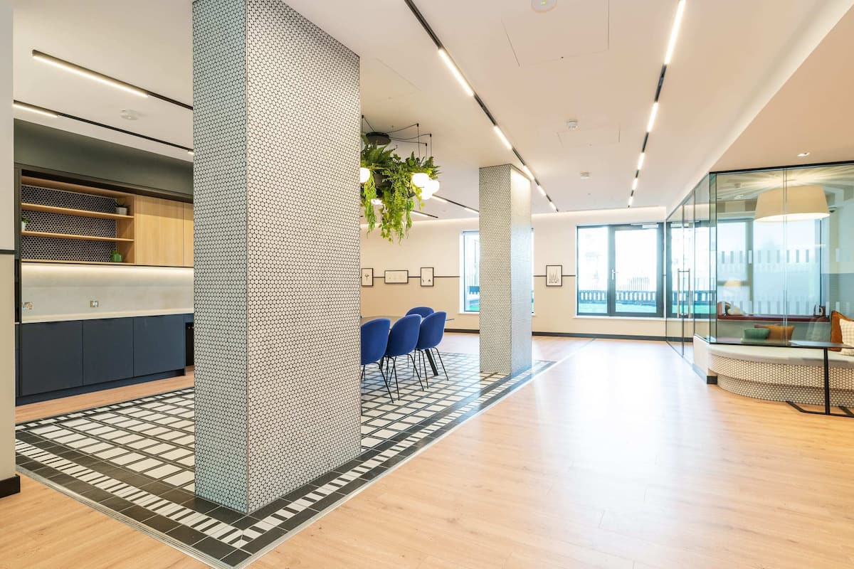 A modern office space with a reception area, seating, and a large window.