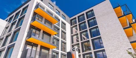 A multi-story building with balconies, large windows, and a clear sky.