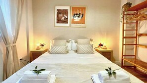 A hotel room with a large bed, two nightstands, a wooden ladder, and two framed pictures on the wall.